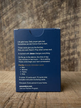 Catholic Prayer Cards — Pax & Ora family prayer card deck in a navy blue tuck box on a rustic wooden surface.