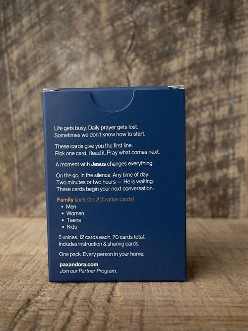 Catholic Prayer Cards — Pax & Ora family prayer card deck in a navy blue tuck box on a rustic wooden surface.