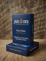 Catholic Prayer Cards — Pax & Ora Prayer Starter pack with 60 prompts in a navy blue tuck box on a wooden surface.