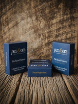 Catholic Prayer Cards — Pax & Ora The Sacred Seasons deck in navy blue tuck boxes on a rustic wooden surface.