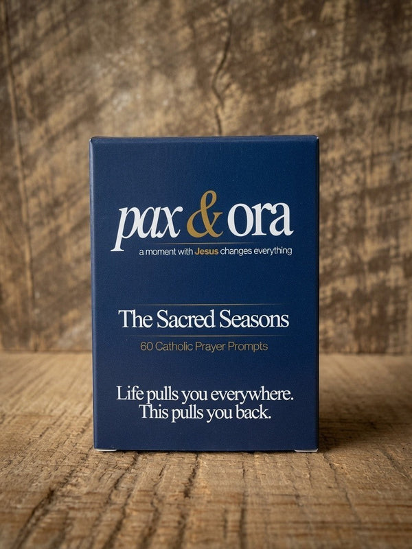 Catholic Prayer Cards — Pax & Ora The Sacred Seasons deck in a navy blue box with white and gold text on wood surface.